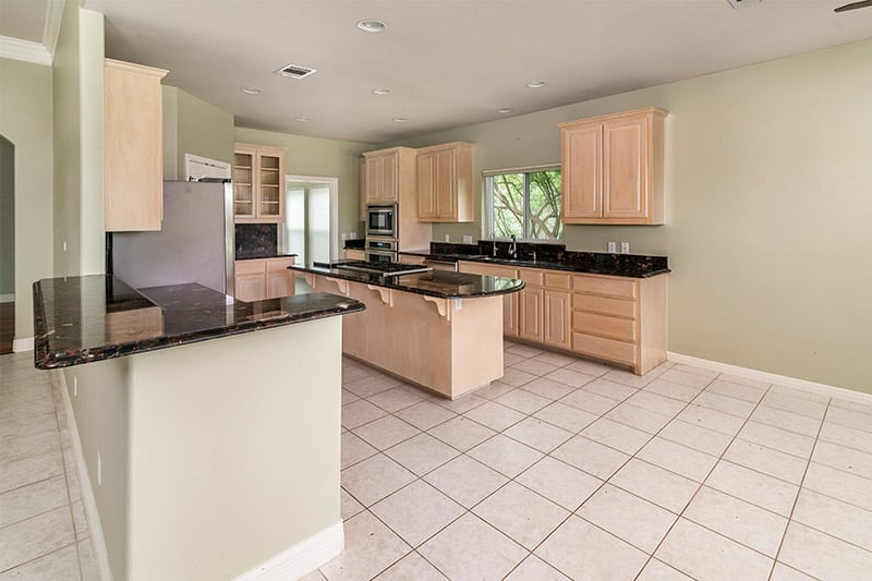 Outdated kitchen with tile countertop and light wood cabinets before remodel