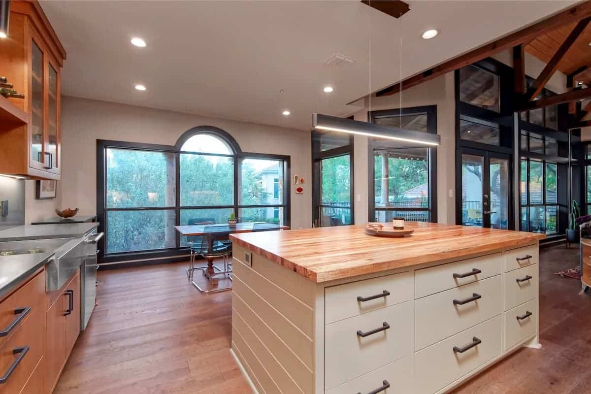 Open kitchen with exposed wood beams, large island, and wood countertops